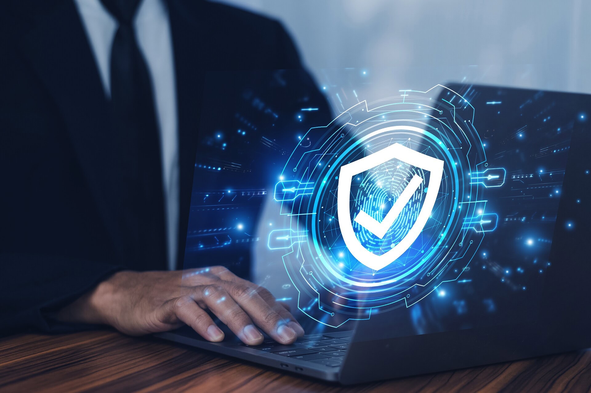 Person Typing on a Laptop With a Security Icon Above it
