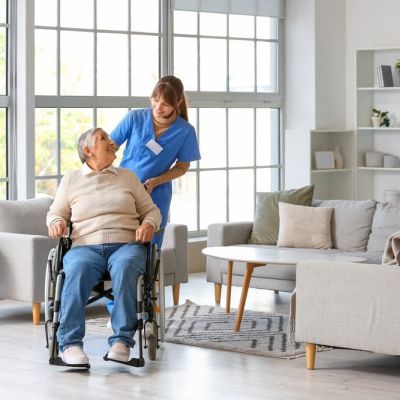 Carer Pushing an Elderly Person in a Wheelchair Whilst They Smile at Each Other