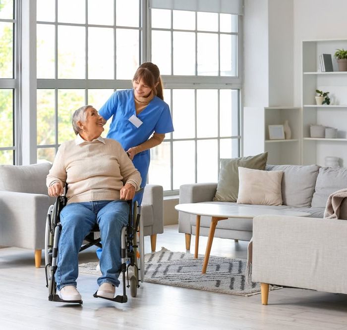 Carer Pushing an Elderly Person in a Wheelchair Whilst They Smile at Each Other
